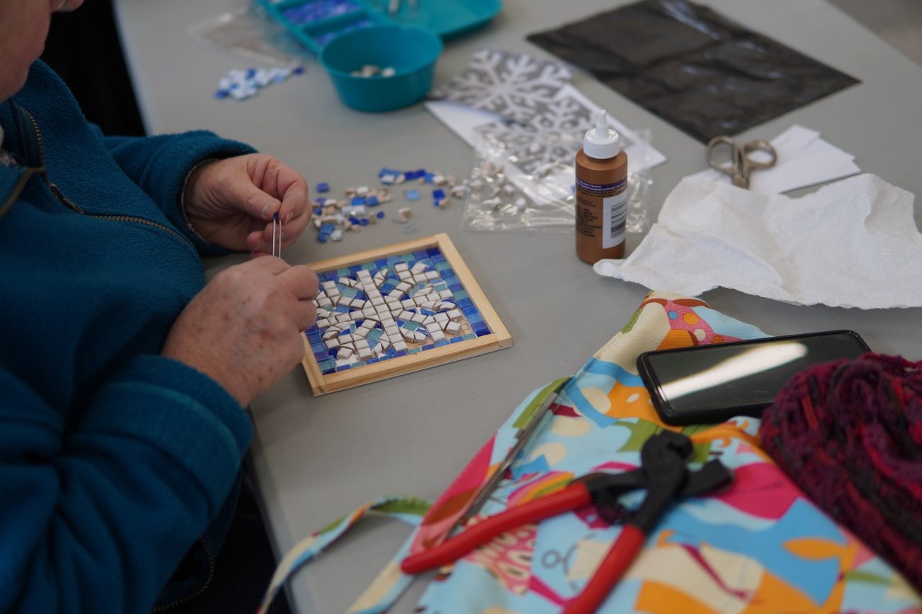 A student's snowflake mosaic in smalti taking shape in a wooden frame